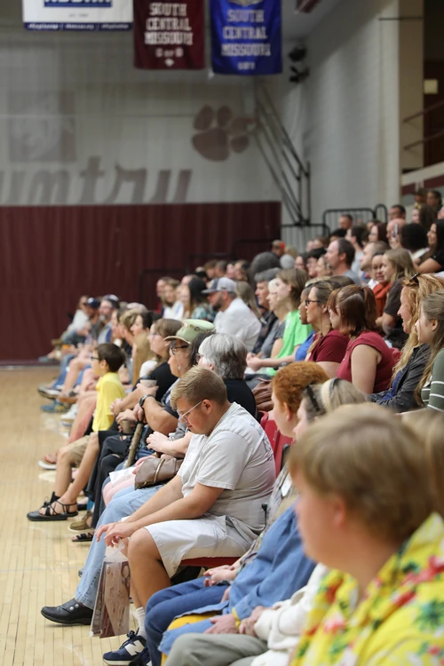 Group of people sitting in gymnasium.